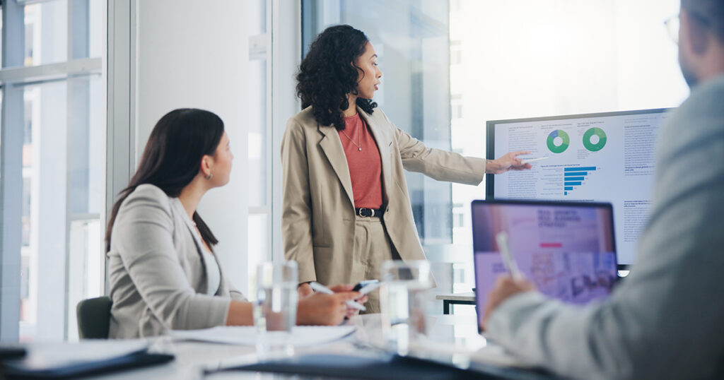A woman points to a presentation in a meeting