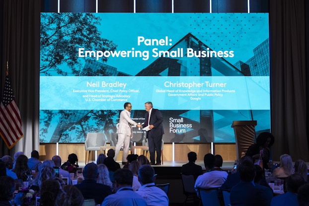  Neil Bradley of the U.S. Chamber of Commerce shaking hands on stage before an interview with Christopher Turner of Google.