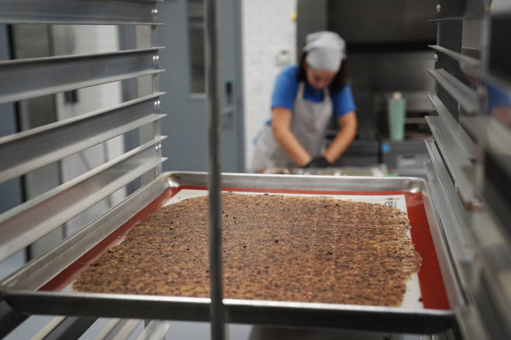 Jina Wye’s assistant Grace Gregg cuts limu-cracker batter at the Wahiawā Value-Added Product Development Center Wednesday, Sept. 17, 2025, in Wahiawā. The center makes producing her “Made in Hawaiʻi” crackers easier with facilities and amenities usually owned by mass-production companies. (Kevin Fujii/Civil Beat/2025)