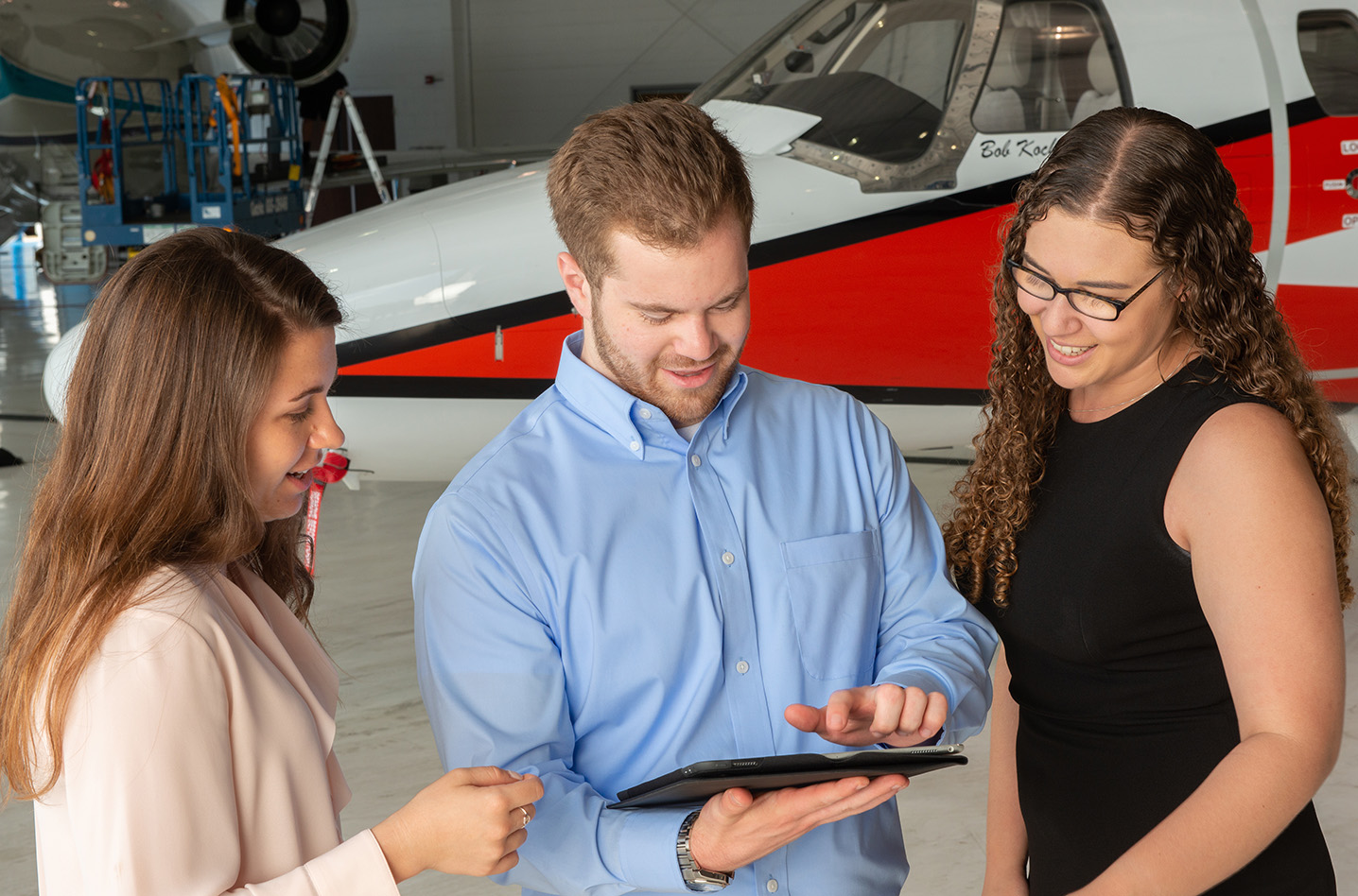 Young professionals in an aircraft hangar looking at an iPad