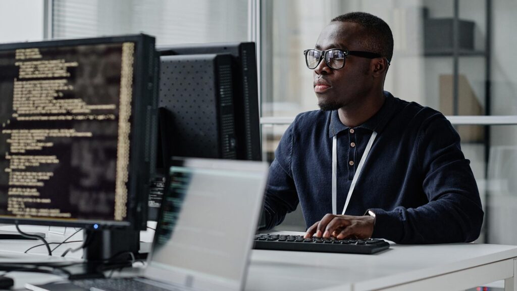 A man working on code at his desk in an office.