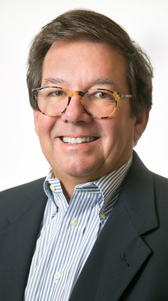 Headshot of a man wearing a gray sport coat and a blue striped shirt.