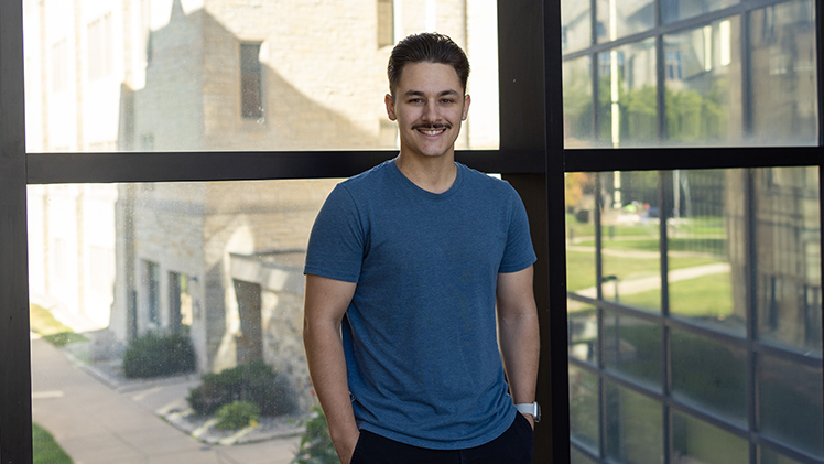 Portrait of UToledo business student Blake Villarreal, who is standing in front of an indoor window.