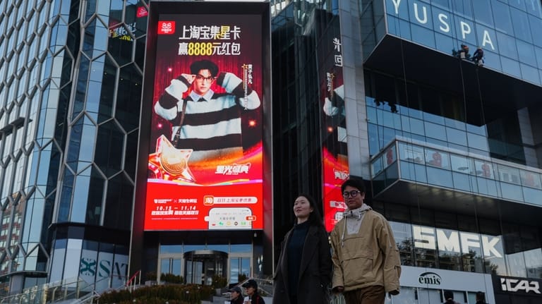 People walk by an advertisement billboard promoting Tmall's Singles' Day...