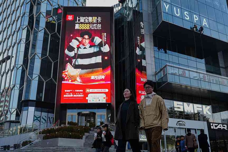 People walk by an advertisement billboard promoting Tmall's Singles' Day sale at a popular shopping district in Beijing on Nov. 10, 2025. (AP Photo/Andy Wong)