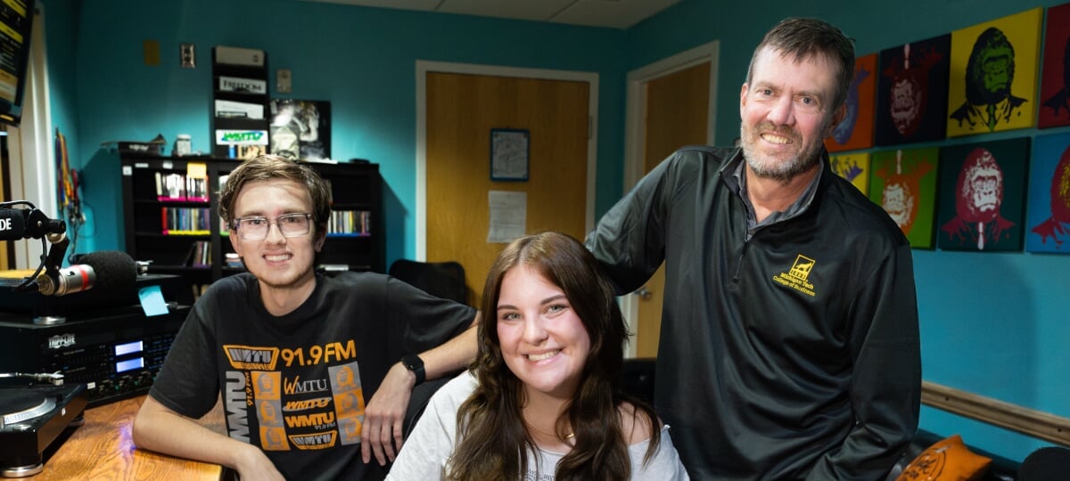 Two Michigan Tech students and their classroom instructor together in the WMTU DJ booth.