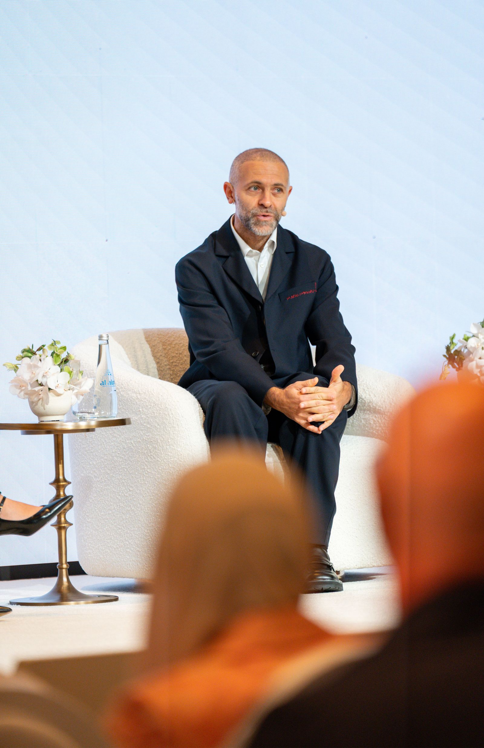 Image may contain Person Sitting Blazer Clothing Coat Jacket Adult Footwear and Shoe