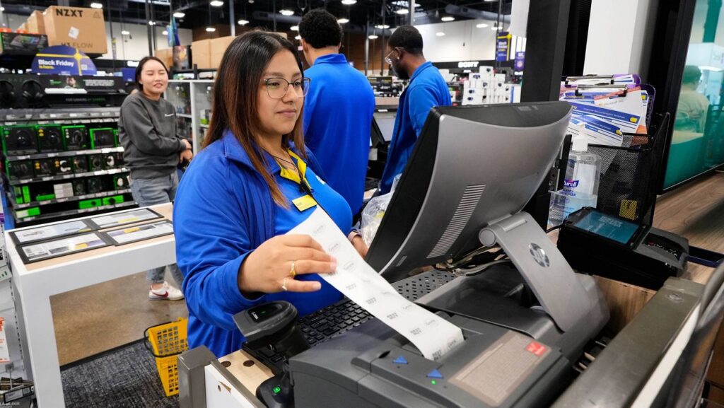 Abril Renteria, an Apple certified advisor, helps a customer check out after their purchase at a Best Buy store, Wednesday, Nov. 26, 2025, in Dallas. (AP Photo/Tony Gutierrez)