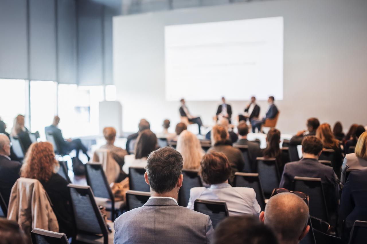Participants attend a panel session during a business conference. (Adobe Stock Photo)