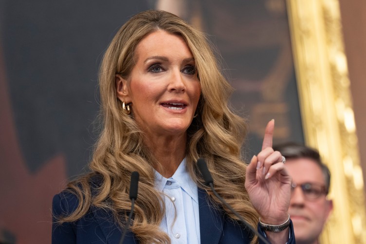 A woman points upward with one finger while speaking.