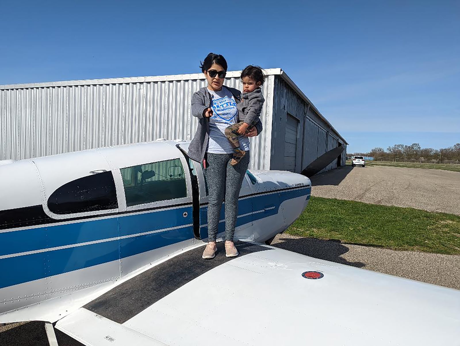 Roopsi Narayan (Left) Narayan's wife, summer of 2022. She is holding their son, Abhiraj, while standing on the wing of her husband's Mooney airplane. CONTRIBUTED