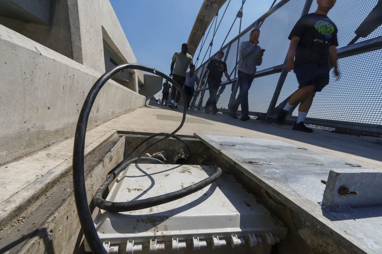 A vandalized high-voltage electrical box, stripped by copper wire thieves, sits along the Sixth Street Bridge as pedestrians walk by in Los Angeles in August 2024.