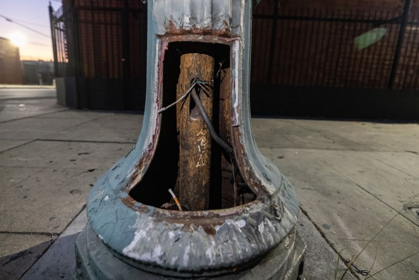 Exposed cut wires hang from a historic streetlight at Broadway and 23rd Street in downtown Los Angeles, a casualty of theft, vandalism and neglect, on Monday, Oct. 6, 2025.