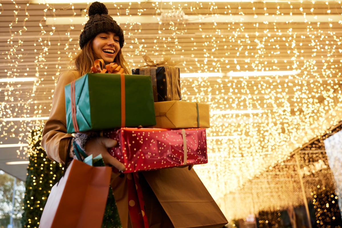 Person holding wrapped gifts inside a mall.