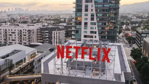 Getty Images The roof of the Netflix offices in Los Angeles with large red NETFLIX  sign in foreground and city scape in the background
