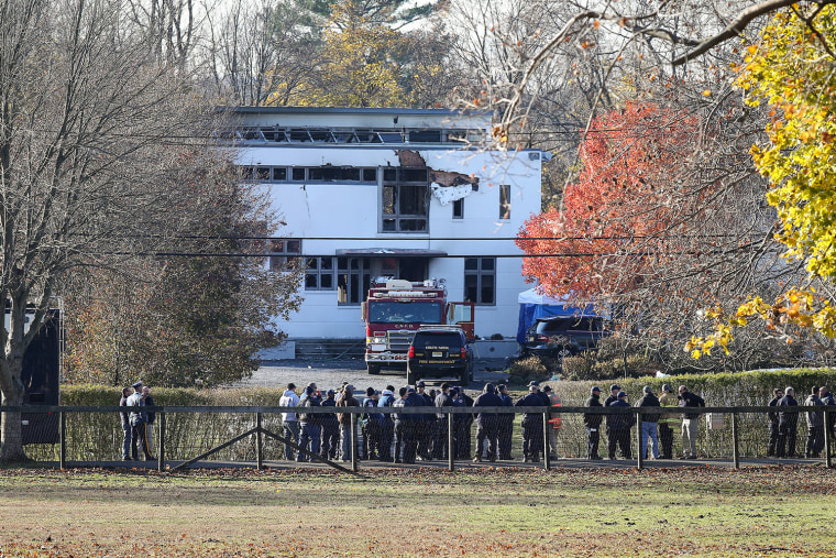 People stand outside of a burnt house