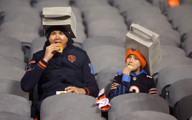 Chicago Bears fans wearing cheese grater hats eat in the stands before the NFC wild-card game between the Chicago Bears and the Green Bay Packers at Soldier Field in Chicago on Jan. 10, 2026. (Chris Sweda/Chicago Tribune)