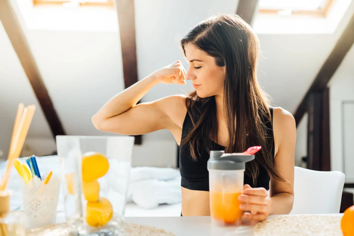 Woman at home drinking orange flavored amino acid vitamin powder