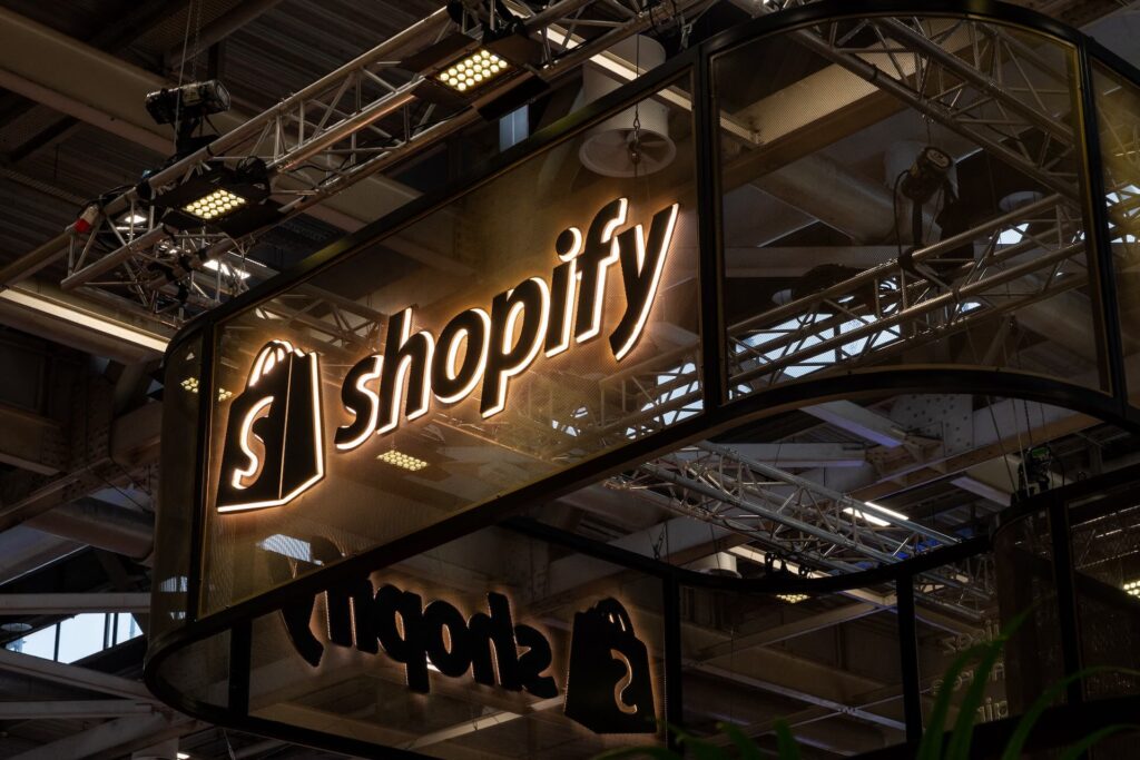A lit up Shopify sign and logo in the rafters of a trade show
