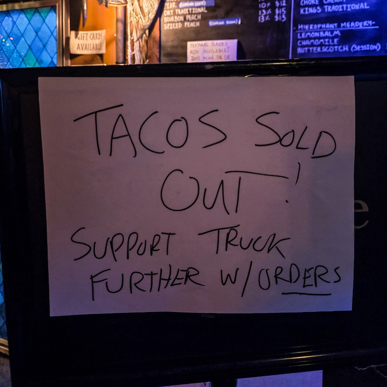 "Tacos sold out! Support truck further w/ orders" sign