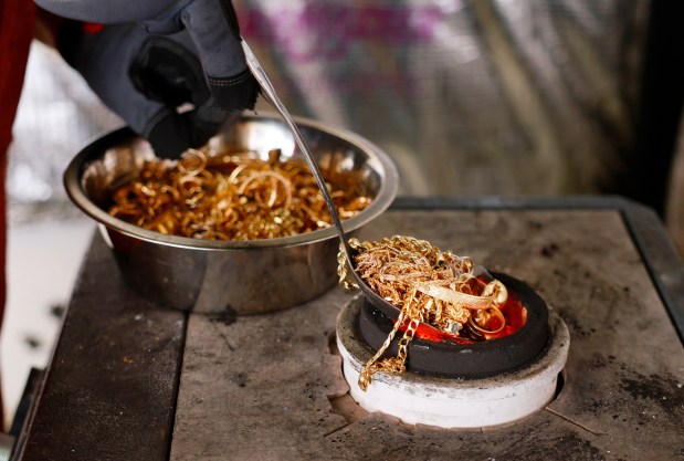 Josh Morelock of Gold Refinery of San Diego puts gold coins and jewelry into a melting furnace to be melted into bars . (K.C. Alfred / The San Diego Union-Tribune)