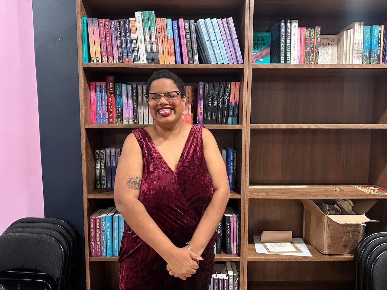 Woman in red dress smiling in front of bookshelves