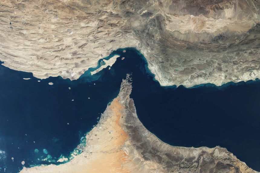 A satellite view of the Strait of Hormuz, a strategic waterway between Iran and Oman that links the Persian Gulf to the Arabian Sea. This vital energy chokepoint handles nearly 20% of global oil.