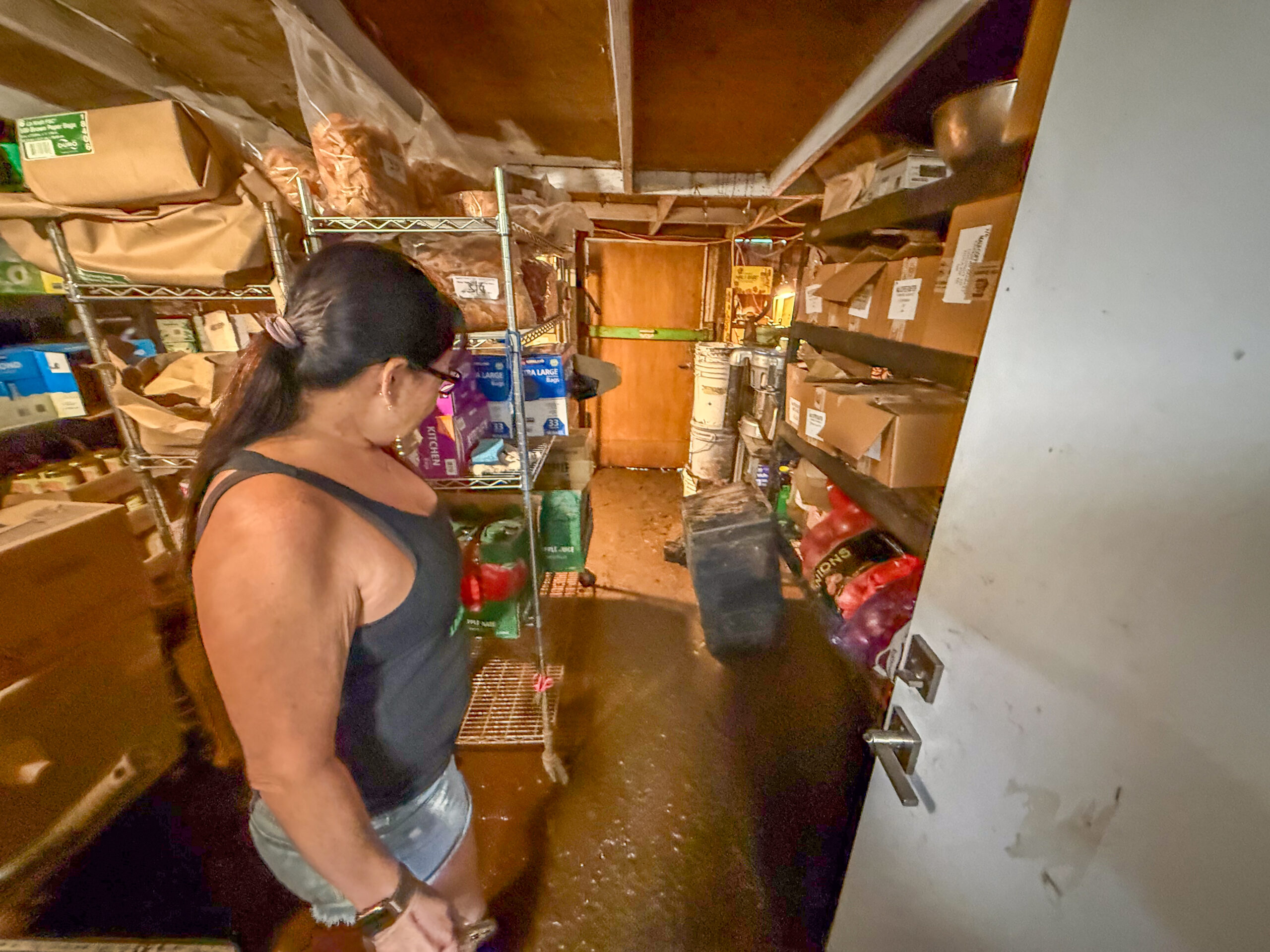Sachi Friedmann, owner of Farmer's Market Maui, shows the mud that made its way into the building during the Kona low storm of March 13 and 14, 2026, despite about 100 sandbags and plastic on the outside. HJI / Cammy Clark photo