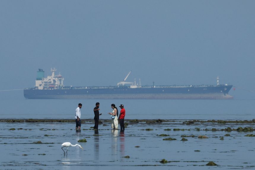 Tourists watch marine life, with the MT Desert Kite oil tanker carrying Russian oil in the background, at Narara Marine National Park in the Arabian Sea, Gujarat, India, on March 11 , 2026.